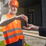 Male construction worker passing keys to house
