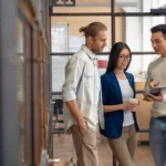 Three young business professionals standing together and discussing over business report